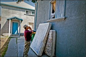 Mr. Daclan yells through an open window of a Stockton house where dogs were guarding the front door. A neighbor came out, but knew nothing of the student he was hoping to locate.