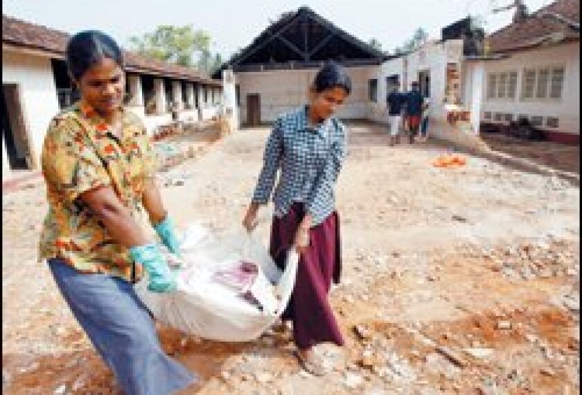 Teachers at a school in the seaside village of Ginota in southern Sri Lanka carry muddy, water-soaked books and other educational materials that were damaged during the Dec. 26 tsunami.