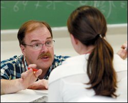 Younger brother Dan Szymkowiak works with a student during a precalculus class at Mundelein High.