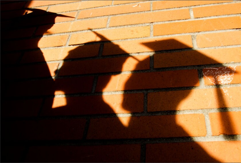 Shadows of Walla Walla (Wash.) High School seniors waiting to enter graduation are cast on a school wall.