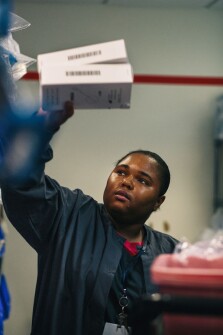 Lakisha Hogan, 23, the first intern hired through Project SEARCH three years ago, stocks shelves at Novant Prince William Medical Center.