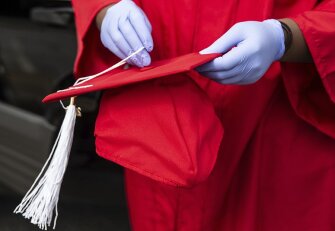 Neiko Pollard wears gloves while trying on a graduation cap during cap and gown pick-up at Page High School in Greensboro, N.C., on Tuesday, April 28, 2020.