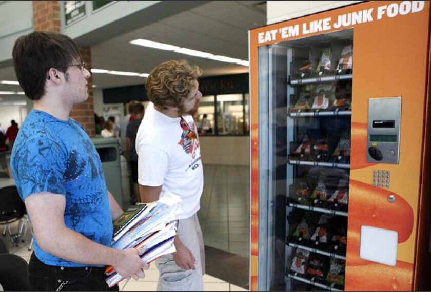 Mason High School seniors Jake Schwartz, left and Jacob Denny check out baby carrots in a vending machine at Mason High School. The machines were installed last month as part of a public relations campaign launched by Bolthouse Farms, a Bakersfield Calif.-based grower. The effort is one of several around the country aimed at making nutritious foods more appealing to students.