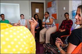 Tia Perry, in yellow, snaps her fingers as Liz Meadows, right, and other fellow teachers smile and laugh during a Happy Teacher Revolution meeting, where moments of mindfulness and guided meditation are shared among teachers at Windsor Hills Elementary School in Baltimore. —Erin Irwin/Education Week