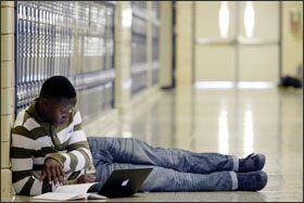 Devonte Coleman, 15, catches up on schoolwork in a Mooresville High School hallway.