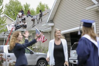 A roofing crew watches as Ellie Tanko graduates in her front yard during a diploma delivery to Xavier High School seniors around Cedar Rapids and Hiawatha on Wednesday, May 13, 2020.