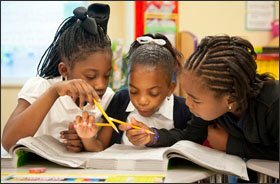 Fifth grade students, from left, Diamon Alton, Alea Payne, and Mar'Reonna Little work on a reading assignment at Barack Obama Elementary School in Pine Lawn, Mo., part of the Normandy school district. The suburban St. Louis district is threatened with bankruptcy because of a state law that requires unaccredited districts to pay tuition for students who transfer to public schools in other districts.