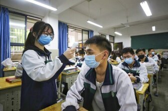 A female student wearing a protective face mask, checks the temperature of her classmates at a high school in Wuhan in central China’s Hubei province, Wednesday, May 6, 2020.