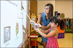 Teacher Kristina Stracke helps a kindergartner during the first week of classes at Fallsmead.