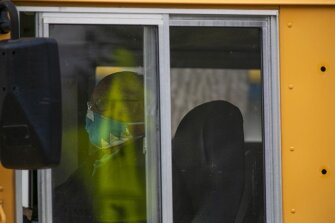 One of the two bus drivers for Willow Creek School wears a mask as he drops off students as the school reopened amid the COVID-19 pandemic, Thursday, May 7, 2020, in Willow Creek, Mont. The other bus driver also wore a mask.