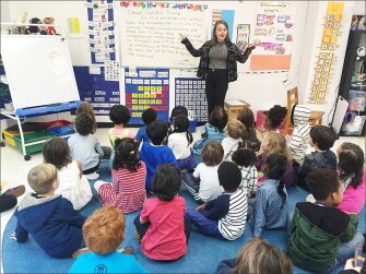 Teacher Emily Silver helps kindergartners at the Co-op School in the Bedford-Stuyvesant community of Brooklyn, draft letters to President-elect Donald Trump. The letters will be mailed to the new President.