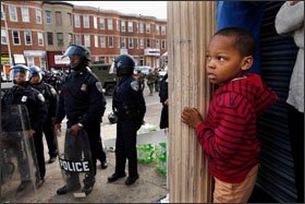 As police gather, Jayden Thorpe, 5, and his mother survey a Baltimore street where a day earlier a CVS drugstore had been looted during rioting that broke out in some parts of the city and prompted officials to close schools the next day.