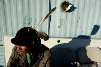 Zintkala Wicasa sits outside his grandmother’s trailer on the Pine Ridge Indian Reservation in South Dakota. The 19-year-old, a graduate of Pine Ridge High School, wears the three eagle feathers he earned–one for completing 8th grade, a second for completing high school, and the last one for completing a sun dance, a traditional religious ritual.