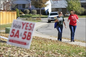 Teachers Denise Hart, left, and Dayna Campbell canvas a neighborhood in Loveland, Colo., to drum up support for local and statewide measures on the Nov. 6 ballot that would bring more money to schools.