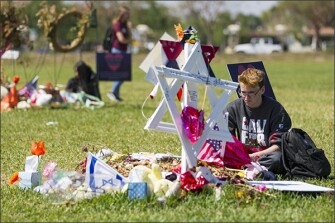 Jeremy Jacobs, 17, a senior at Marjory Stoneman Douglas, stops at a makeshift memorial for a slain student after walking out of school and making his way to Pine Trails Park in Parkland, Fla., on March 14. Hundreds of students at the school walked out of class in protest of gun violence on the one-month anniversary of the Parkland shooting.