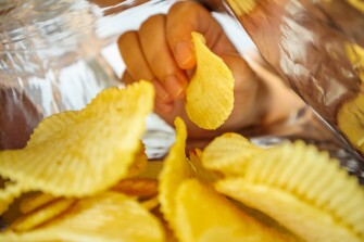 Hand reaching into a potato chip snack foil bag for chips