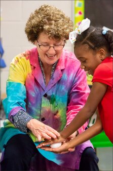 Teacher Julie Neidhardt helps kindergartner Nataya Jones as she attempts to break a raw egg by squeezing it in her hands.