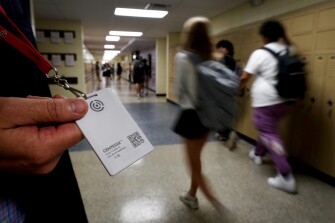 Brent Kiger, Olathe Public Schools' director of safety service, displays a panic-alert button while students at Olathe South High School rush between classes, Aug. 19, 2022, in Olathe, Kan. The district introduced the buttons, which allow staff to trigger a lockdown that will be announced with flashing strobe lights, a takeover of staff computers and a prerecorded intercom announcement, at the start of this school year as part of $2.1 million plan to make district schools more secure. In the wake of a deadly elementary school shooting in Tennessee earlier this week, state lawmakers across the country are moving forward with school safety measures.