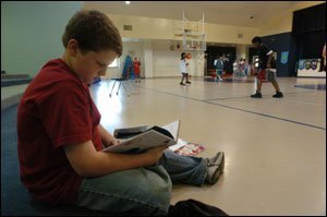 Basketball Poet and fifth grade student Taylor Maggard reads a poem during gym class as classmates start a game of basketball.