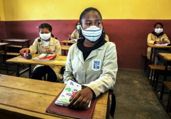 Masked students sit in their class, after being given a herbal extract believed to protect from COVID-19, in Antananarivo, Madagascar, Thursday, April 23, 2020. Schools were reopened after being closed for a month due to the spread of coronavirus. Students have to drink the extract as schools resume classes where they now are seated one to a desk instead of two, for social distancing.