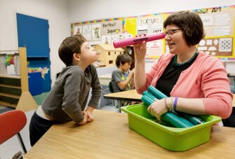 Special education teacher Elizabeth Rosenberry, right, makes eye contact with Ian Tokay through a “boomwhacker”at PS4Q in the borough of Queens, N.Y.