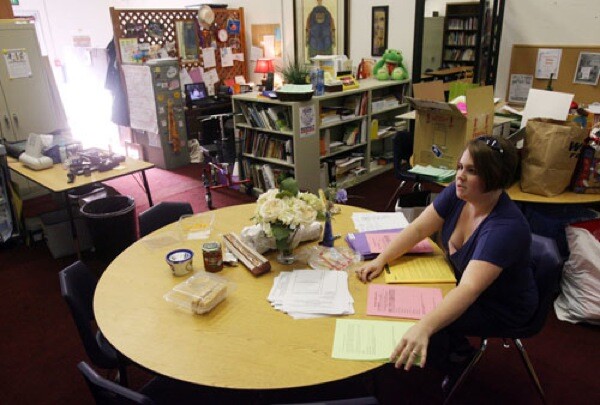 Librarian Liz Tanner used to play racquetball in the converted athletic club where she now works. Tanner prepares packets in a room that serves as the principal's office, staff lounge, volunteer work room, and houses three teachers' offices.