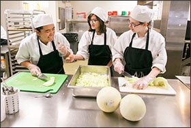 In the kitchen at Denver Montessori Junior/Senior High School, 8th graders Melody Elizalde, Nateya Chavez, and Lily Kleinfeld-Hamilton, from left to right, help prepare lunch for the entire school.