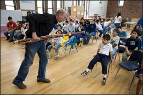 Dennis Michael, a member of a quintet from the Chicago Symphony Orchestra, jams on his bassoon in front of Paulo Martinez, 6, and other students at Erie Neighborhood House.