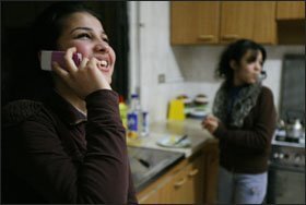 Zuhal Tayeh, 16, left, talks with a friend on her cell phone while at home with her sister Zainab.