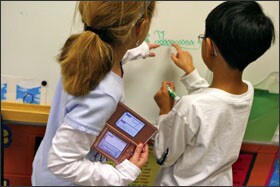 Students at Johns Creek Elementary work on a math problem using a Nintendo DSi, a digital device that is popular among children there.