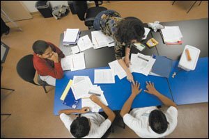 Joyce Moses reviews math with her tutees. They and other low-income students — though only a fraction of those eligible — are getting free assistance.