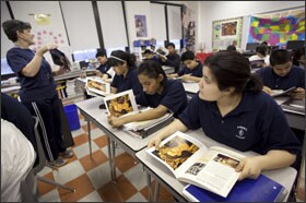 Viviana Herrera, right, searches for character trais as she reads a book about Frida Kahlo during "success time" at the start of the school day at William Finkl Academy, a Chicago public school that is part of the Focused Instruction Process. At left is 8th grade social studies teacher Kathy Pozniak.