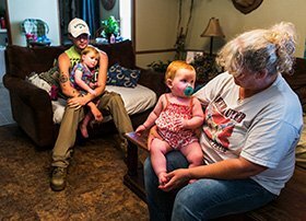 Trey Clayton, left, holds 2-year-old Elliana as his mother, Dana Hamilton, balances his 1-year-old daughter, Evelyn, on her knee at their home in Sarah, Miss. A 2011 paddling led Clayton to eventually drop out of school.