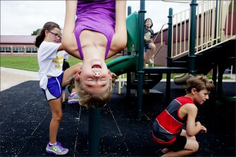 Third grader Elyse Vinton hangs upside down during recess at Eastridge Elementary School in Lincoln, Neb., where schools are now required to report on their progress on student-health-related measures, including the time allotted for recess.