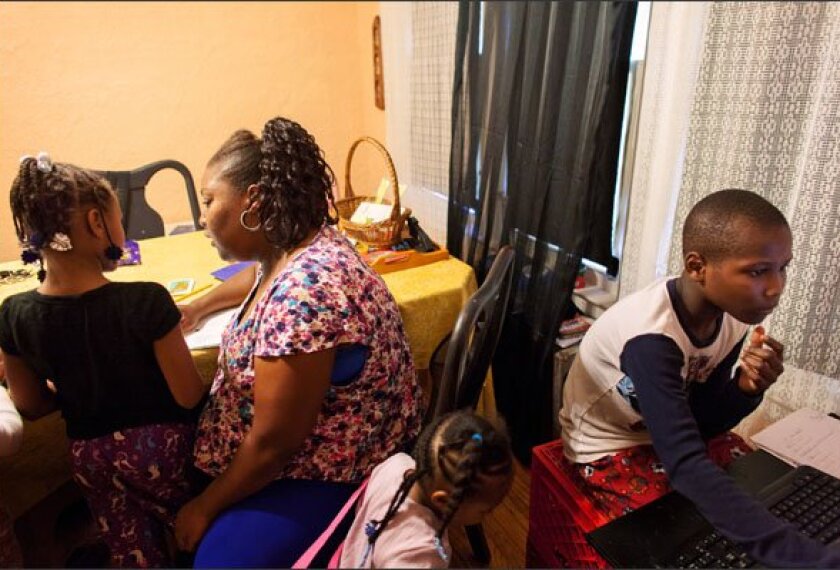 Reginald Cureton, a 12-year-old diagnosed with lead poisoning at age 1, studies alongside his mother, Jeanine, and sisters Novea, 8, and Shekinah, 3, in their Detroit home. New research is exploring ways to counter the negative learning effects of lead exposure.