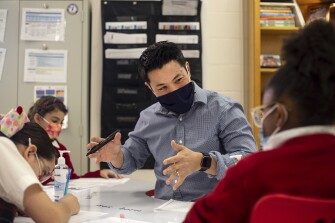 Zachary Chan helps Robyn Pinnix, 9, with an activity in his third grade class at Young Women’s Leadership Academy in San Antonio, Texas on February 7, 2022.