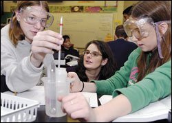 Melissa Jaeger, center, an 8th grade science teacher at Lakeshore Middle School in Grand Heaven, Mich., helps Emily Thomas, left, and Sara Sturgill perform a heat conduction experiment. Schools are gearing up for federal science-testing requirements.