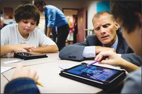 Steven Webb, the superintendent of schools in Vancouver, Wash., watches as students Damon Reinhardt, 12, left, and Philip Morgan, 13, work on a geography project using the app “Pic-Collage” in a 7th grade combined language arts/Washington state history class at Alki Middle School.