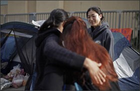 Seventh grade teacher Erica Cho, who is being laid off, watches as Gaudy Alvarado, foreground right, gets a hug from Isabel Ceballos, a sixth grade teacher who is also being laid off outside John Liechty Middle School in Los Angeles.