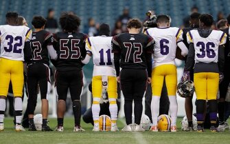 Camden High School (white jerseys) and Pleasantville High School players stand for a moment of silence before the two teams resumed their football game on Wednesday that had been interrupted by gunfire last Friday night. Ten-year-old Micah Tennant died from his injuries in the shooting.