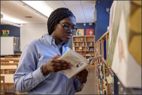 Emmanuella Kobara, an 11th grader at New Visions Charter High School for the Humanities on the John F. Kennedy campus, looks for books in the library.