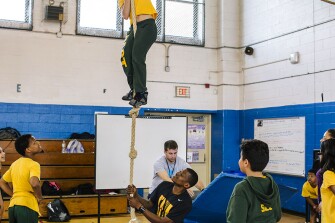 Sixth graders work at rope-climbing during a gym class.