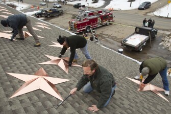 Volunteers, from left, Adrian Szepietowski, Guy Veneruso, Craig Schultz and Len Sabia, work on the installation of 26 stars on the roof of the Sandy Hook fire station Tuesday, Jan. 1, 2013, in Newtown, Conn. The stars were made and installed by a group of local contractors to honor the memory of the victims of the Sandy Hook school shooting. Nearly three weeks after the shooting rampage, classes are set to begin again for the Sandy Hook students Thursday, Jan. 3, 2013 at a repurposed school in the neighboring town of Monroe.