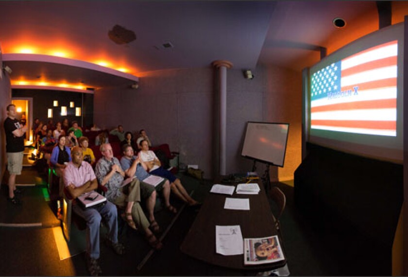 Lecturer Larry Knapp, left, leads a discussion of the opening scene of the movie "Malcolm X" at the Facets Summer Film Institute for teachers in Chicago, in a panoramic photo made up of multiple images.