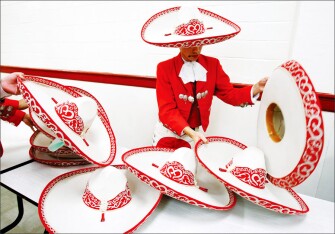 David Arredondo, a junior, sorts through sombreros for the right fit as members of Mariachi Estrella, a music group from Premont High School, prepare to perform in the Texas High School Mariachi Competition in San Antonio. The event aims to promote music education and enrichment and recognize the state’s top high school programs.