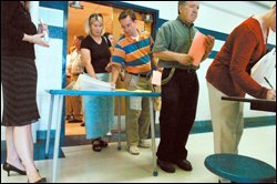 Members of the staff at Iroquois High School pick up surveys prepared by a research group looking at the results of the district's Ramp-Up to Literacy instructional system before an all-faculty meeting after school in the cafeteria.