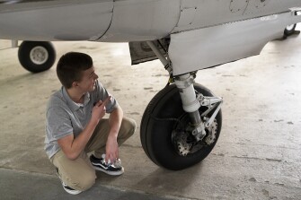 Sophomore Luke Moitoza, part of the aviation program at Magruder High School, takes a look at the landing gear of a plane during a visit to the Montgomery County Airpark in Gaithersburg, Md., on April 6, 2022.