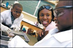 Ashley Armstead, a college student working at the school, helps Darius Beckford, left, and Andrew Harvey dissect a sheep brain.