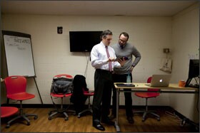 Patrick Larkin, left, the assistant superintendent of the Burlington public schools in Massachusetts, and Andy Marcinek, an instrumental-technology specialist at Burlington High School, chat while viewing an iPad in the “help desk” area of the high school.