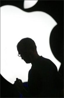 Steve Jobs is silhouetted against the Apple logo during a product launch in 2005.